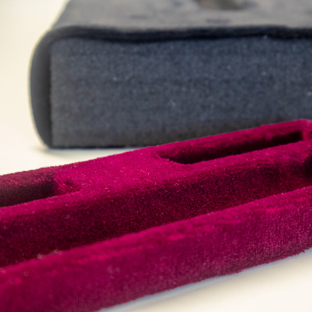 Ein Schaumstoffeinsatz in einem Koffer, der mit rotem Samt kaschiert wurde.